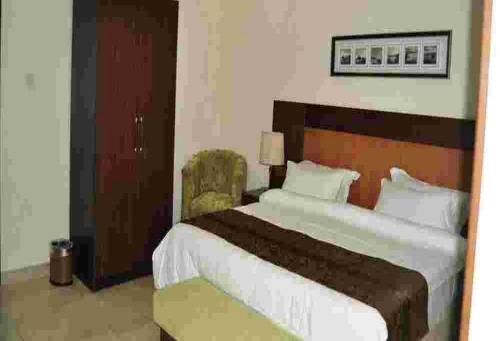 een hotelkamer met een groot bed en een stoel bij Room in Lodge - De Brass Suites Hotel in Yenagoa