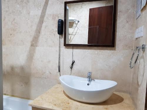 ein Badezimmer mit einem weißen Waschbecken und einem Spiegel in der Unterkunft Full Moon Hotel - Premiere in Owerri