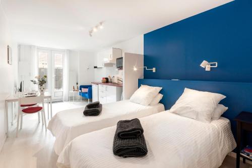 2 łóżka w pokoju z niebieską ścianą w obiekcie Les Logis de Marcoussis w mieście Marcoussis