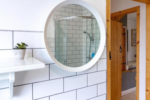 a bathroom with a mirror and white subway tiles at The Shoe Box cottage with allocated parking in Malmesbury