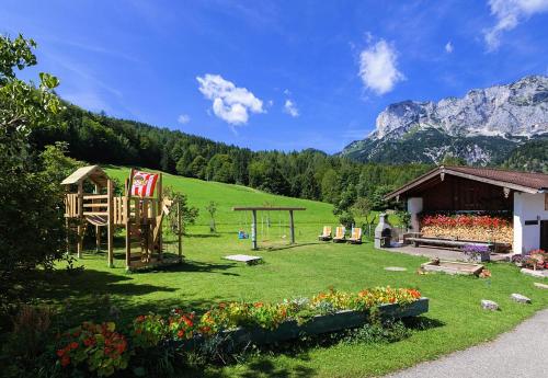 a garden with a playground and a house and mountains at Berghof Lippenlehen in Marktschellenberg