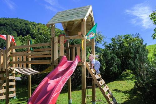 Ein Mann klettert eine Rutsche auf einem Spielplatz hoch in der Unterkunft Berghof Lippenlehen in Marktschellenberg