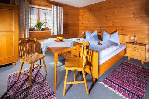 sypialnia z łóżkiem, stołem i krzesłami w obiekcie Berghof Lippenlehen w mieście Marktschellenberg