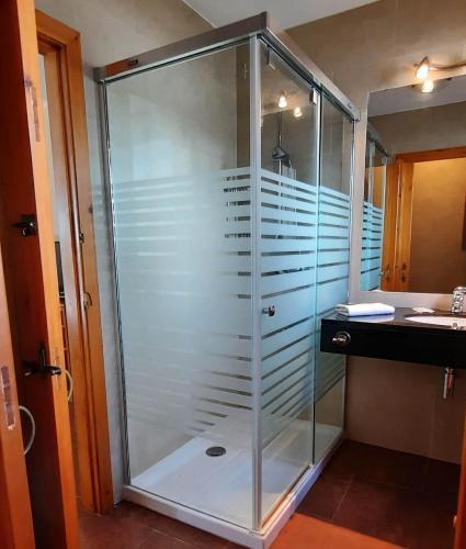 a glass shower in a bathroom with a sink at Homenfun Menorca Playa de Fornells I in Fornells