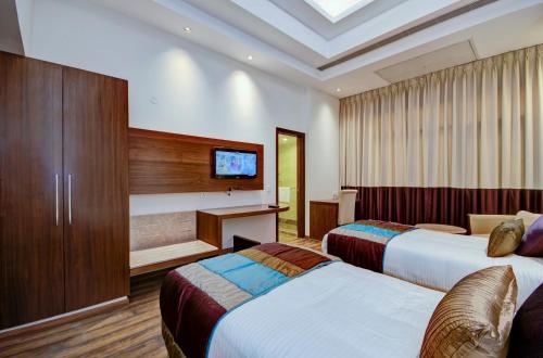 a hotel room with two beds and a television at La Sagrita in New Delhi