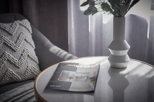 a table with a vase and a magazine on top of a table with at The Remington Orange in Orange