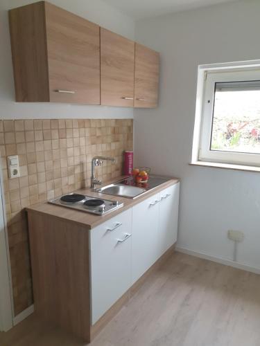 a kitchen with white cabinets and a sink and a window at Am Schloss in Angelbachtal