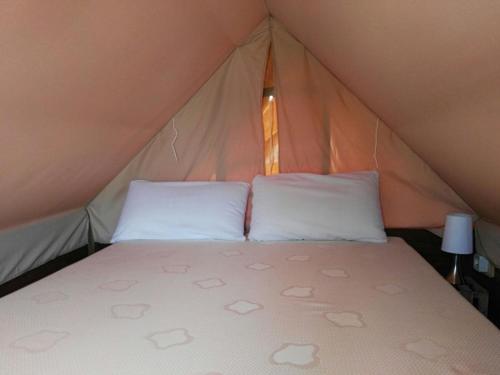 a bed in a tent with two white pillows at Càmping Rural Montori in Ultramort