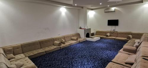 a large room with couches and a flat screen tv at استراحة الخير in Şulbūkh