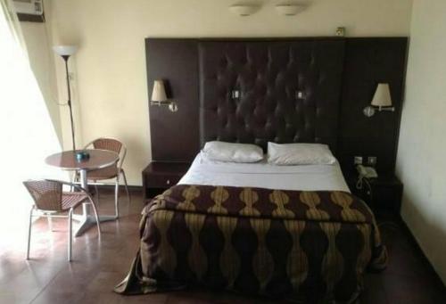 a bedroom with a large bed and a table at Room in Lodge - Nelrose Hotel, Asaba in Asaba