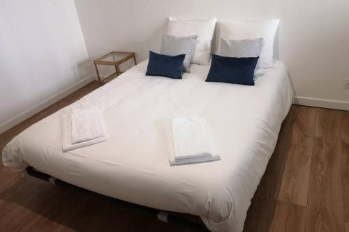 a large white bed with blue pillows on it at Le Duplex des QUAIS in Blois