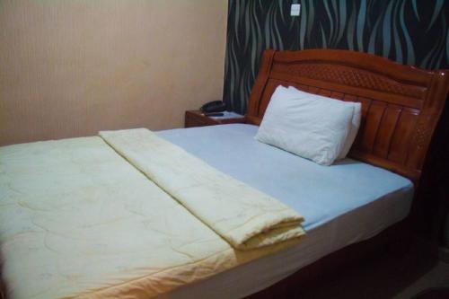 a bed with a wooden headboard and a white pillow at Owees Place-standard in Lagos
