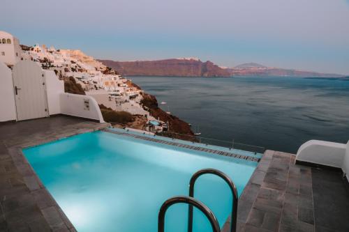 a swimming pool with a view of the water at Santorini Secret Suites & Spa, Small Luxury Hotels of the World in Oia