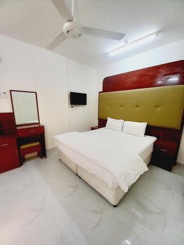 um quarto com uma grande cama branca e uma televisão em Discovery Duqm Apartment em Duqm