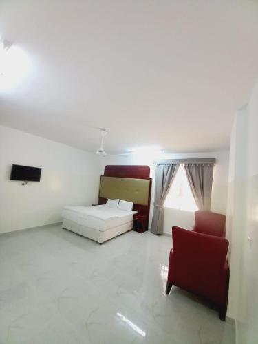 a bedroom with a bed and a couch and a chair at Discovery Duqm Apartment in Duqm