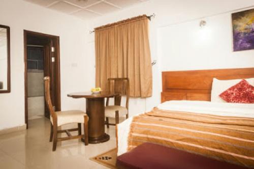 a bedroom with a bed and a table and a chair at Whispering Palms Resort in Lagos