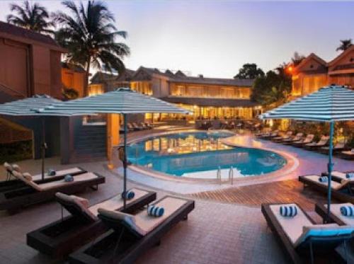 Room in Lodge - Whispering Palms Resort في لاغوس: مسبح مع كراسي الصالة والمظلات