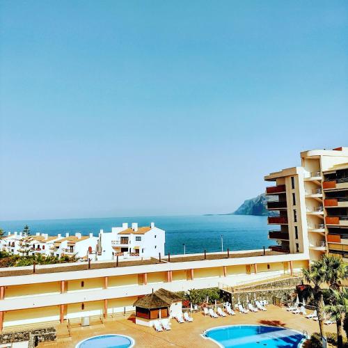 a view of a resort with two swimming pools and the ocean at Balcón Los Gigantes Puerto de Santiago in Puerto de Santiago