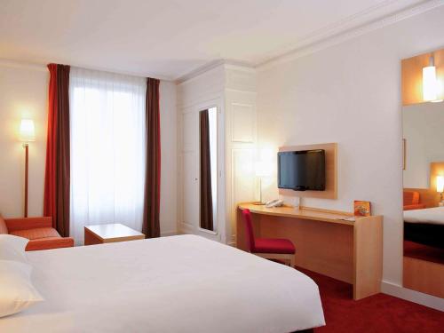 a hotel room with a bed and a desk with a television at ibis Lyon Centre Perrache in Lyon
