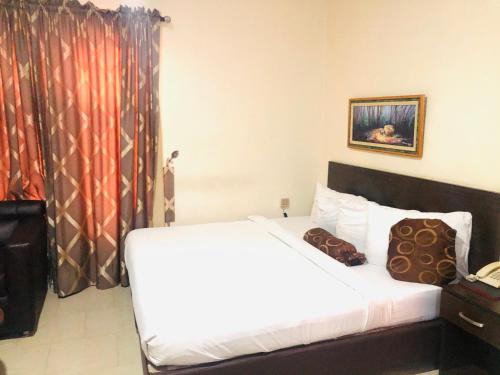 a hotel room with a bed with white sheets at Mayors & Diplomats Suites Opebi in Eregun