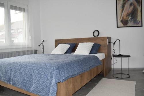a bedroom with a bed with blue and white sheets and a window at Apartman WALKOW in Vukovar