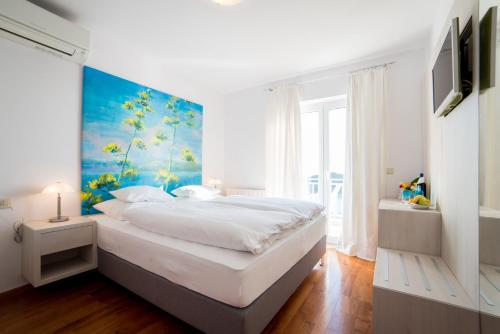 a bedroom with a large bed with a painting on the wall at Rooms Raič in Dubrovnik