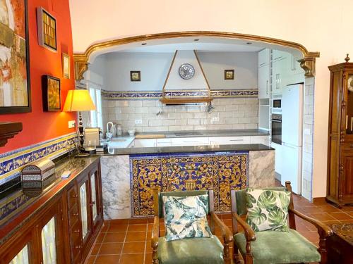 eine Küche mit orangefarbenen Wänden und einer Theke mit 2 Stühlen in der Unterkunft 4 bedrooms villa with private pool enclosed garden and wifi at Los Palacios y Villafranca in Los Palacios y Villafranca