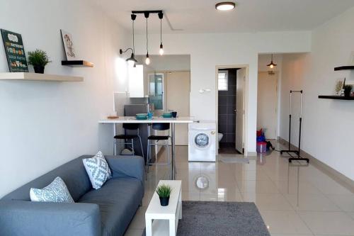 ein Wohnzimmer mit einem blauen Sofa und einer Küche in der Unterkunft Home Comfort Homestay @ Galleria Equine Park in Seri Kembangan