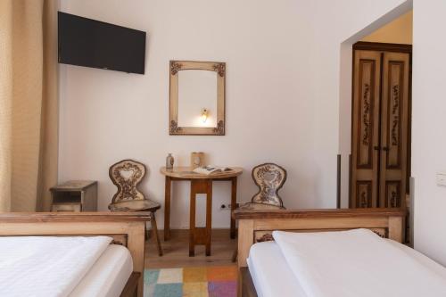 a bedroom with two beds and a table and a mirror at Pensiunea Sibiel in Sibiel