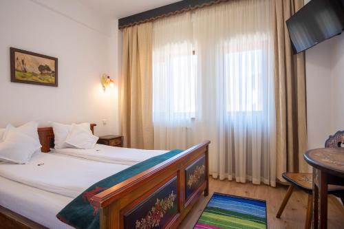 a bedroom with a bed and a table and a window at Pensiunea Sibiel in Sibiel