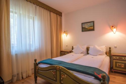 a bedroom with a bed with white sheets and a window at Pensiunea Sibiel in Sibiel