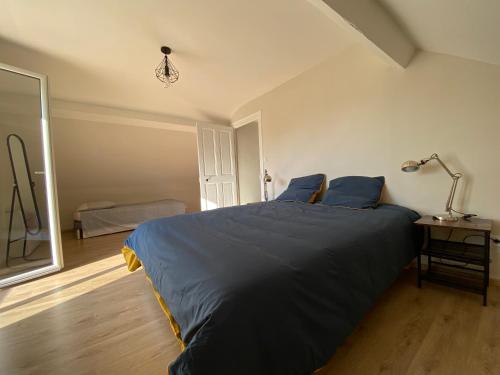 1 dormitorio con 1 cama con sábanas azules y lámpara en Le Pavillon de l'Hermitage - Spa ouvert d'Avril à Octobre, en Tain-lʼHermitage