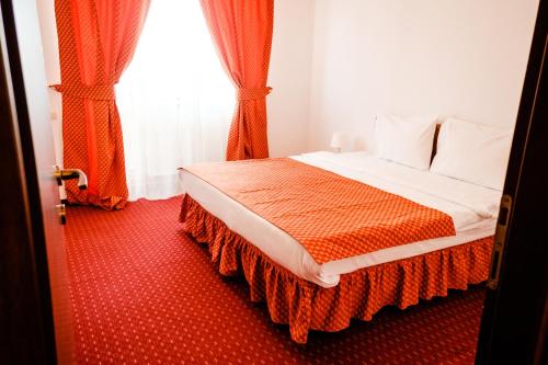 a bedroom with a bed with orange curtains and a window at West Gate Studios in Bucharest