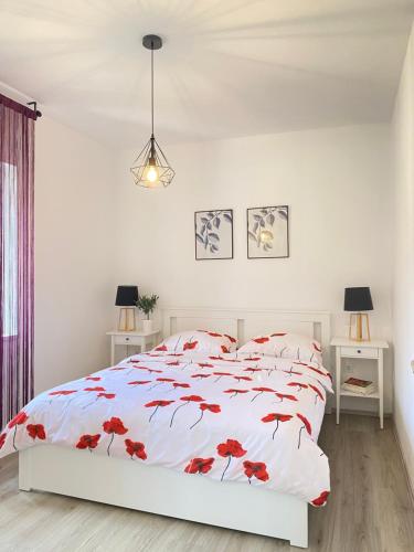 a white bedroom with a bed with red flowers on it at Holiday House Lucia in Sukošan