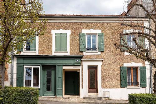 une maison en briques avec portes et fenêtres vertes dans l'établissement Les Logis de Marcoussis, à Marcoussis
