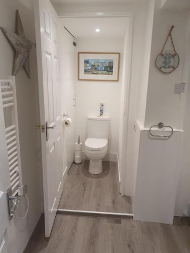 a white bathroom with a toilet and a picture on the wall at Beachcomber B&B in Tenby