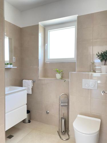 a bathroom with a toilet and a window at Holiday House Lucia in Sukošan