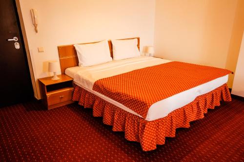 a bedroom with a large bed with an orange blanket at West Gate Studios in Bucharest