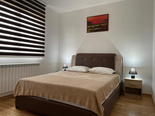 - une chambre avec un grand lit et une fenêtre dans l'établissement Royal Residence Apartmani 2, à Pančevo