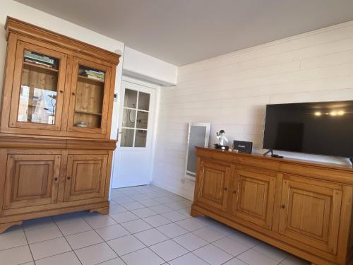 un salon avec une télévision et une grande armoire en bois dans l'établissement L'Aéroplage, Appartement Standing Rénové Vacances 40mètres plage, à Berck-sur-Mer