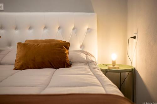 - un lit avec un oreiller et une table avec une lampe dans l'établissement Toffee Matteotti - MY PLACE SANREMO, à Sanremo