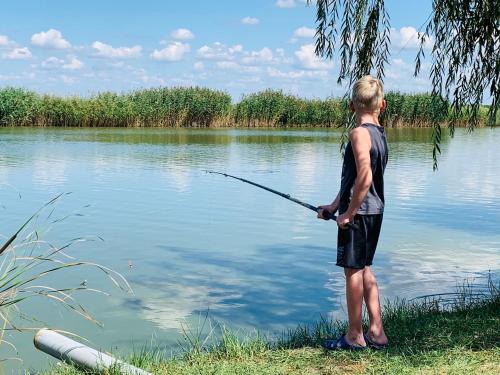a man standing in the water holding a fishing rod at Happy Mammy Bababarát Vendégház Fészek utca in Orosháza