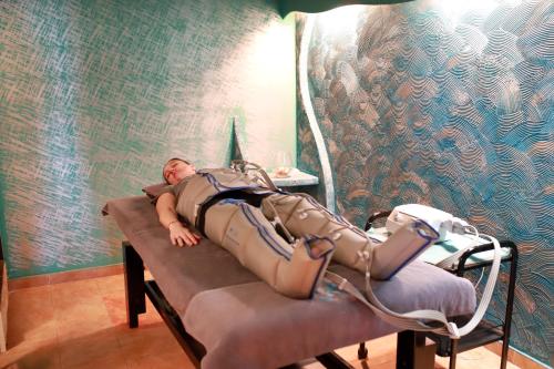 a man laying in a bed in a hospital room at SPA Hotel Olymp in Velingrad