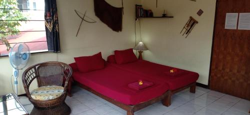 a bedroom with a red bed with a chair and a window at Homestay Galpera Papua in Jayapura