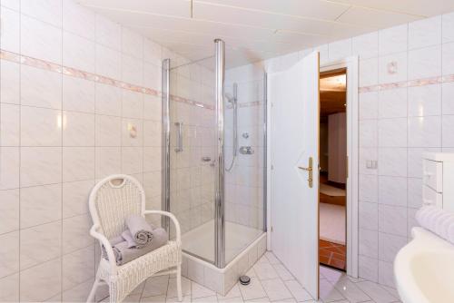 a white bathroom with a shower and a chair at Ferienwohnung Sonja in Elmen