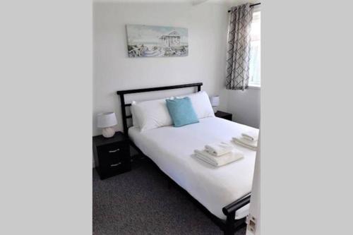 a bedroom with a bed with white sheets and blue pillows at Exceptional Chalet near to Beach, Broads & Gt Yarmouth in Great Yarmouth