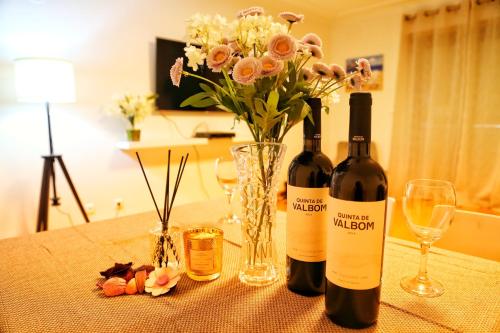 two bottles of wine sitting on a table with flowers at Bom dia Parque Nações LisboaZ in Lisbon
