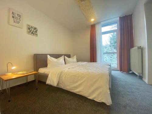 a bedroom with a bed and a table and a window at Akzent Hotel Höhenblick in Mühlhausen im Täle