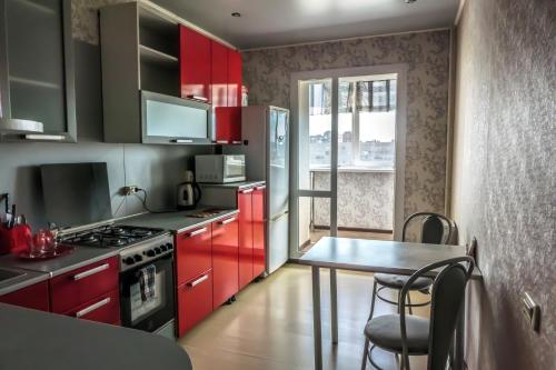 チェレポヴェツにあるКомфортные апартаментыのキッチン(赤いキャビネット、テーブル、椅子付)