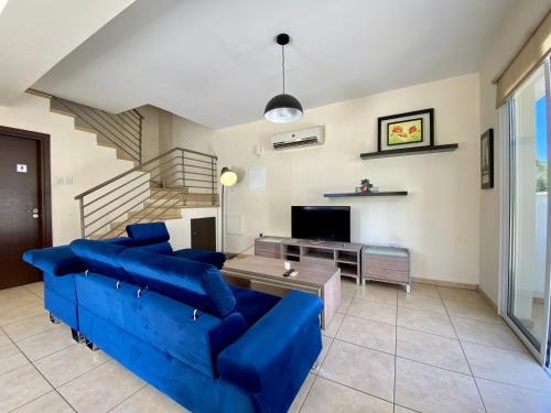 a living room with a blue couch and a table at Sunny Cyprus in Paralimni